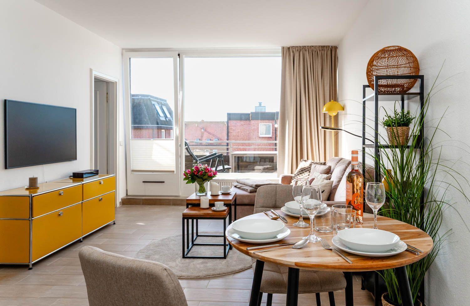 Wohnung mit Essbereich, TV und Balkon. Möbel und Dekoration sind modern.