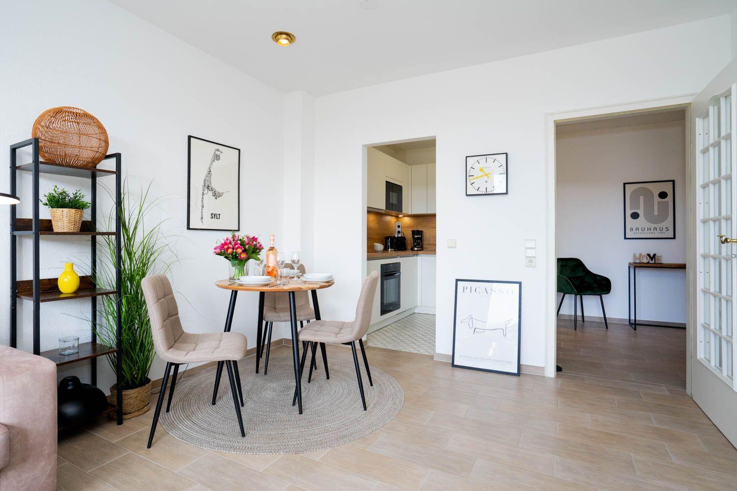 Essbereich mit Tisch, Stühlen und Dekoration. Küche und Schlafzimmer sind sichtbar.