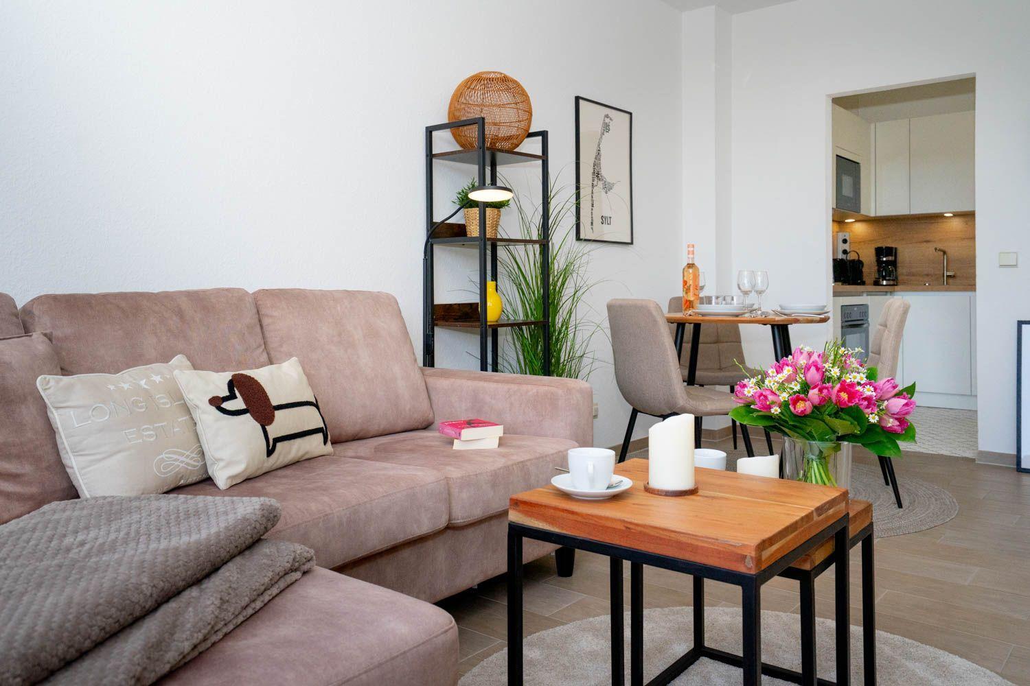 Wohnbereich mit Sofa, Couchtisch und Blick in die Küche.