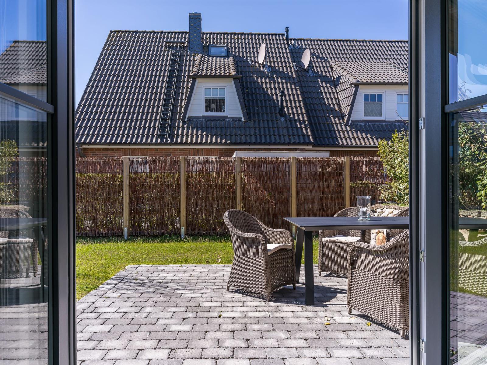 Terrasse mit Sitzgruppe und Blick auf Garten und Nachbarhaus.