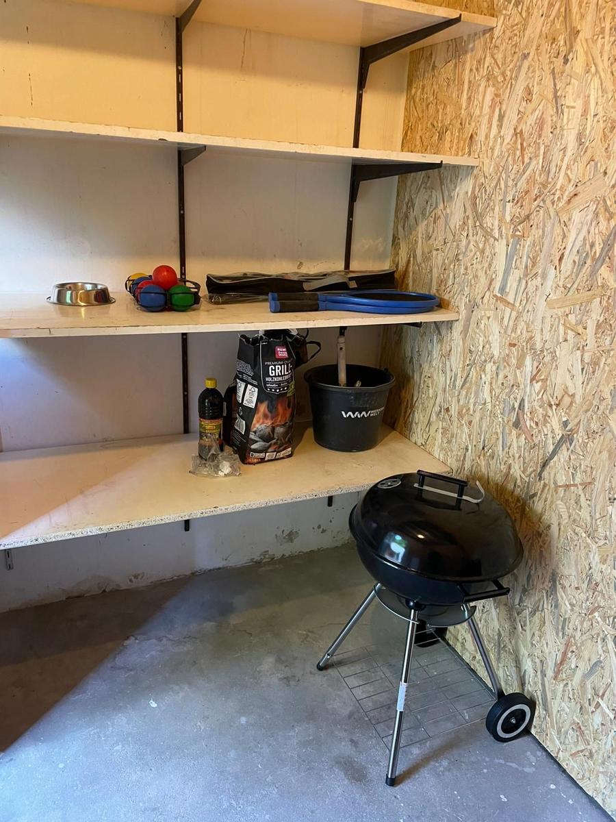 Grillbereich mit Regalen, Grill, Grillzubehör und einem Eimer.