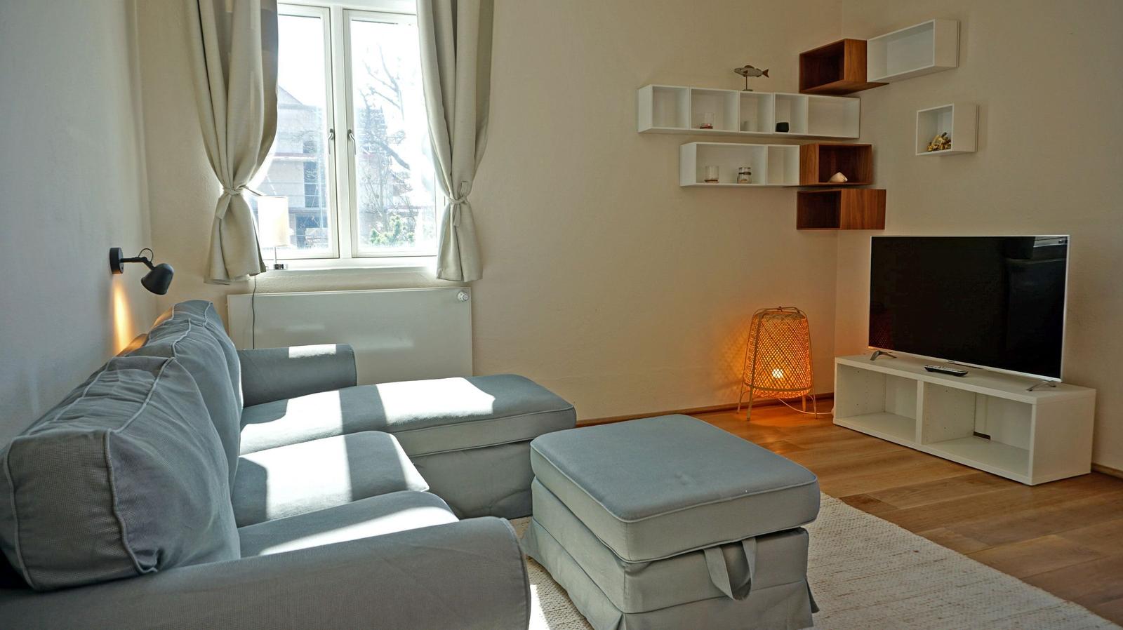 Living room with sofa, TV, and wall shelves.