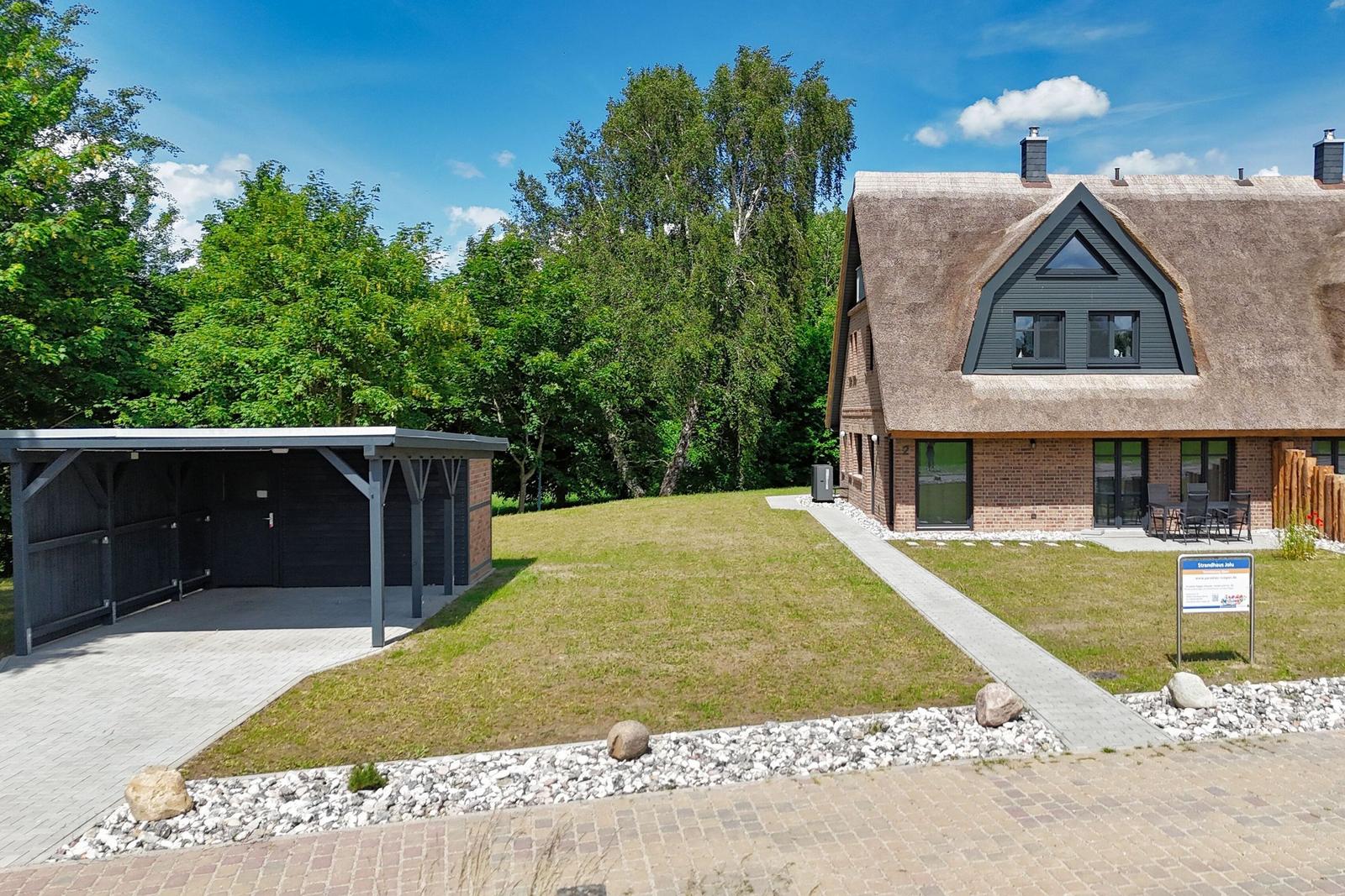 Dorfhaus mit Strohdach, Garten und Carport. Terrasse mit Sitzgelegenheit.