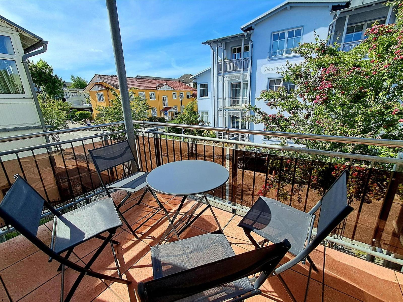 Terrasse mit Tisch und Stühlen. Blick auf Gebäude und Bäume.