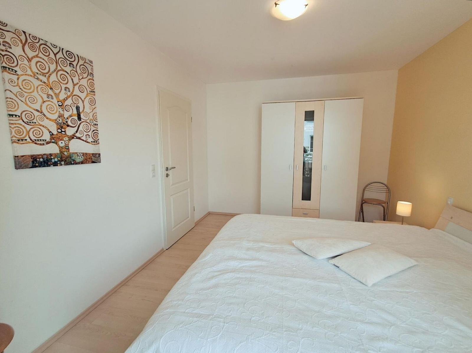 Schlafzimmer mit Bett, Kleiderschrank und Wandbild