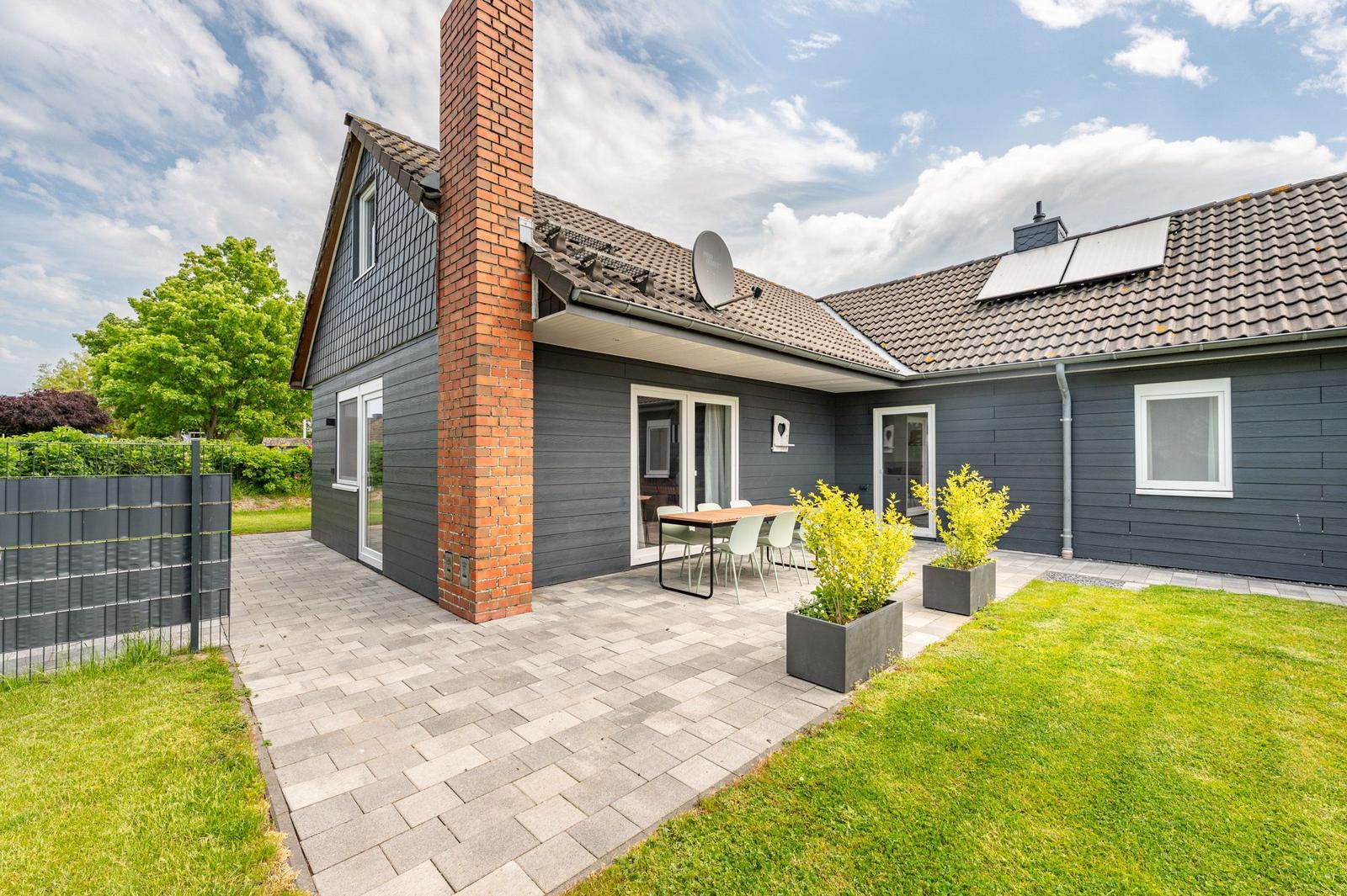 Moderne Villa mit Terrasse, Garten und Satellitenantenne. Holz- und Steinoptik.