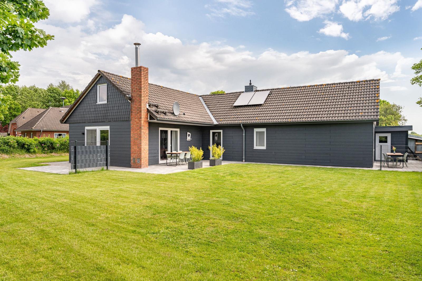 Ein modernes Haus mit großem Garten und Terrasse. Außenbereich mit Sitzgelegenheiten.