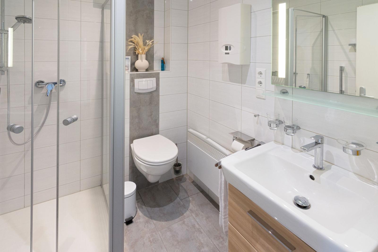 Badezimmer mit Dusche, Toilette und Waschbecken mit Spiegel.