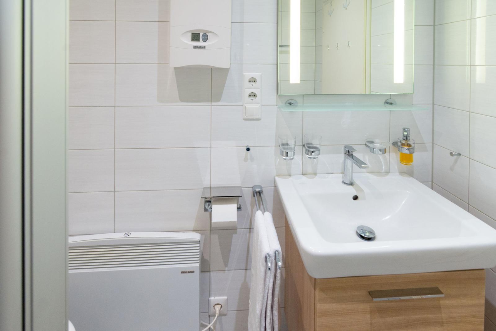 Badezimmer mit Waschbecken, Spiegel, Handtuchhalter und Heizung.