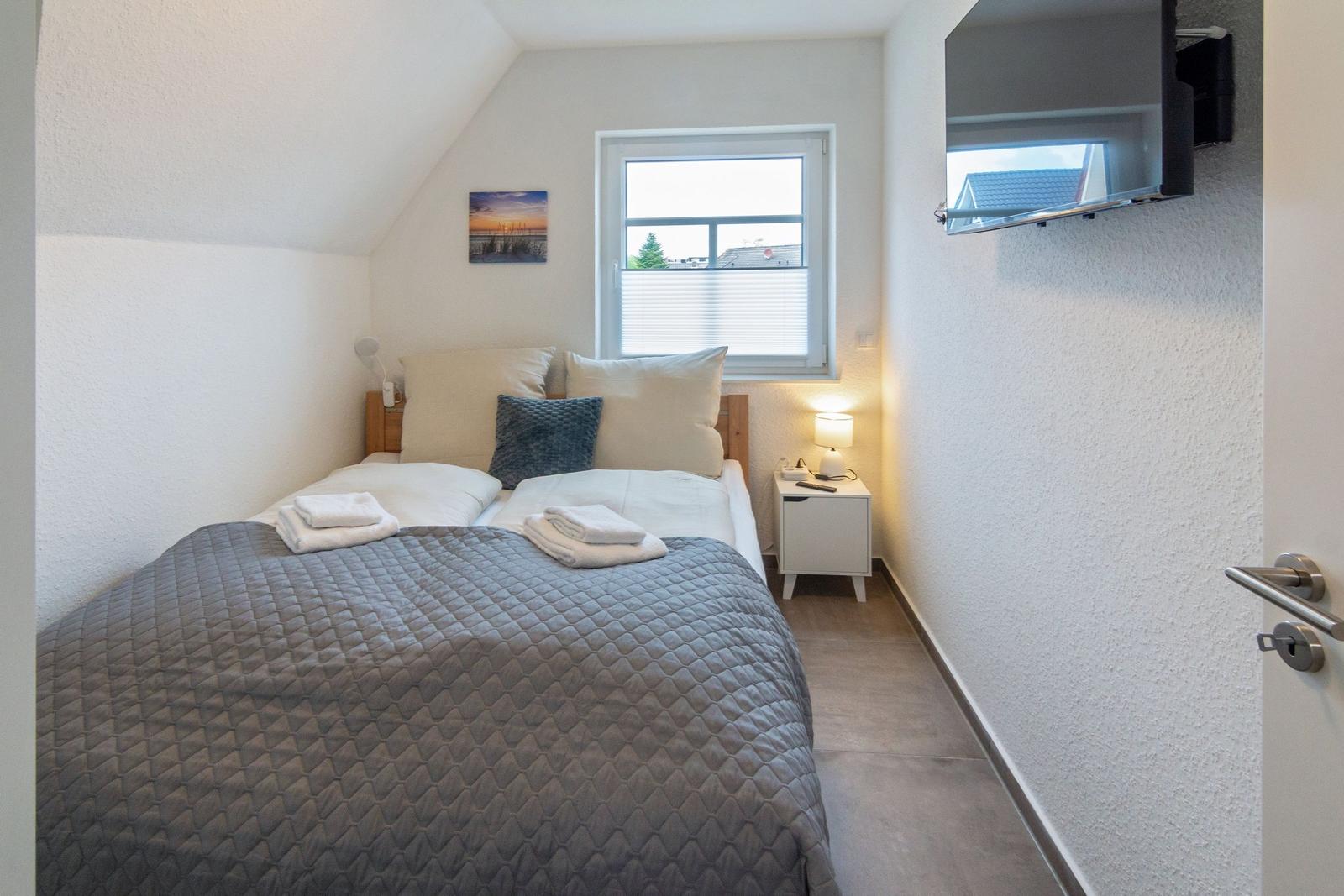 Schlafzimmer mit Doppelbett, Nachttisch, TV und Fenster mit Blick.