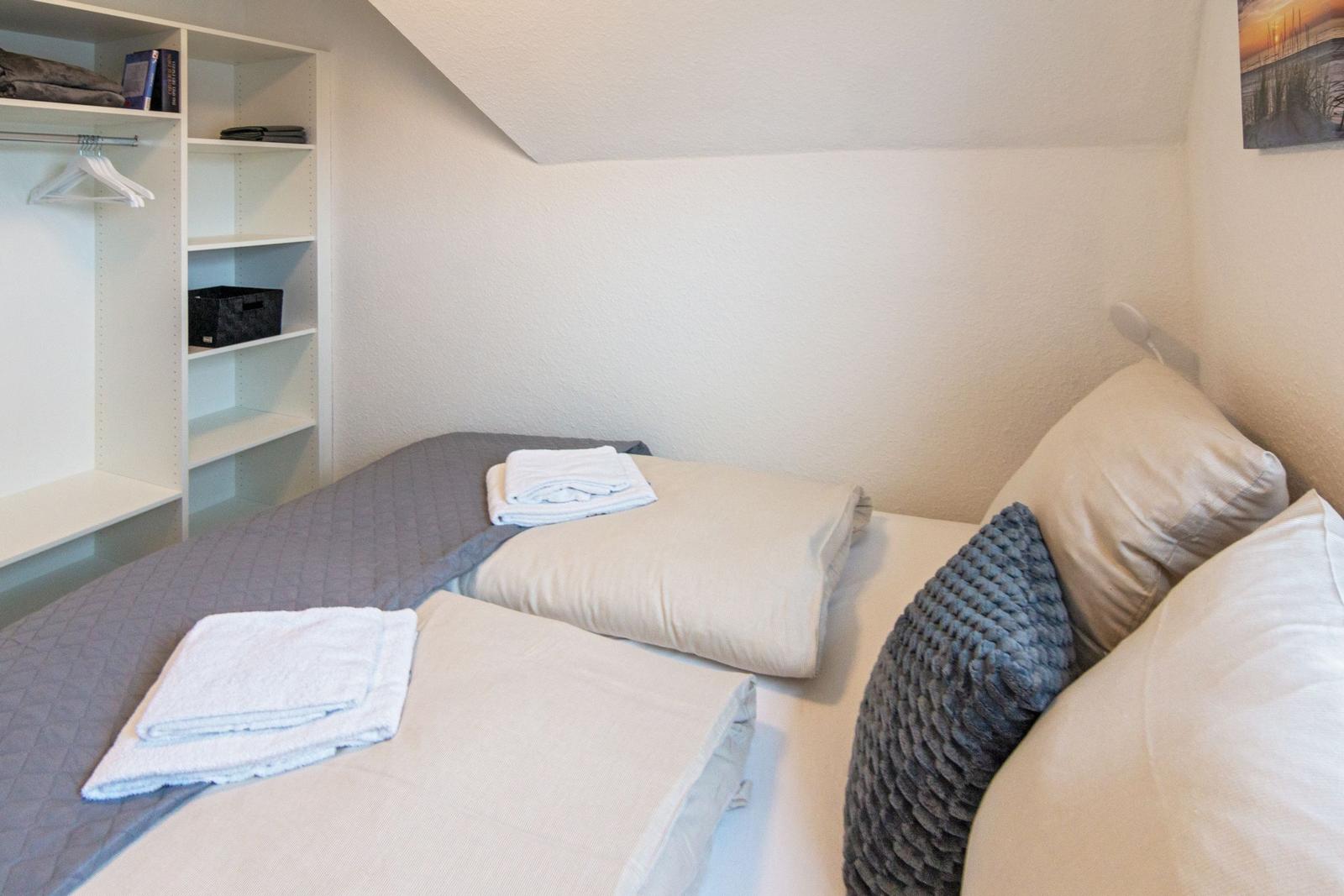 Schlafzimmer mit Bett, Kissen und Kleiderschrank unter Dachschräge.