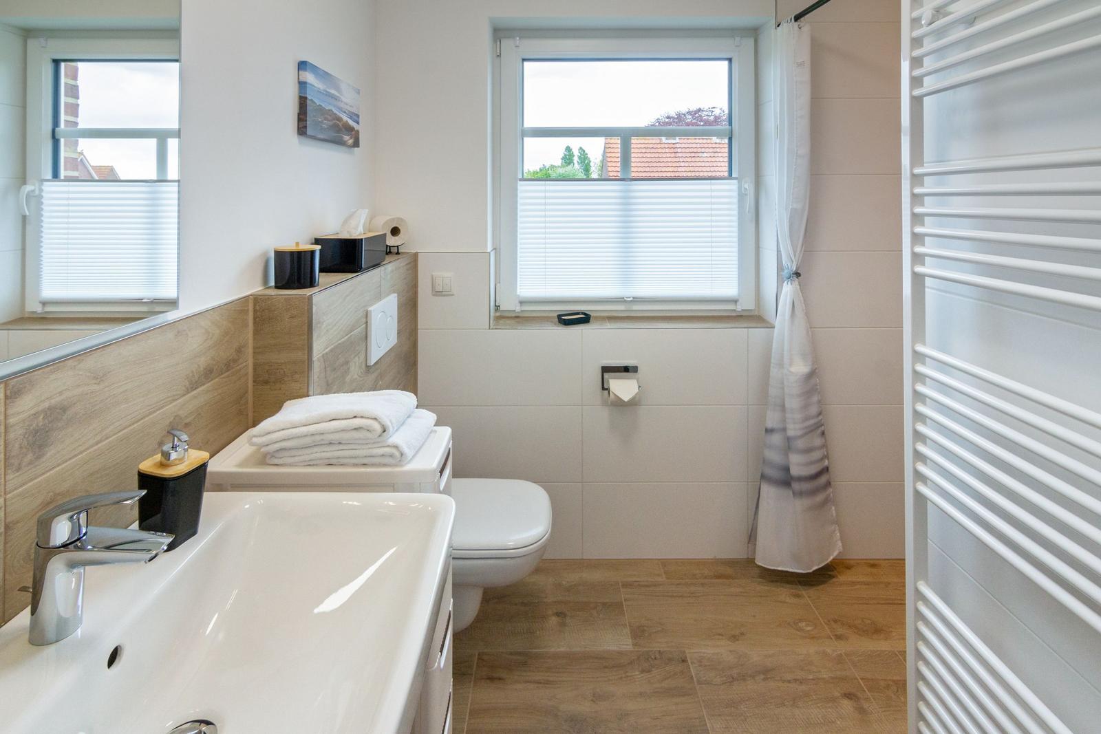 Badezimmer mit Waschbecken, Toilette, Fenster und Heizung.