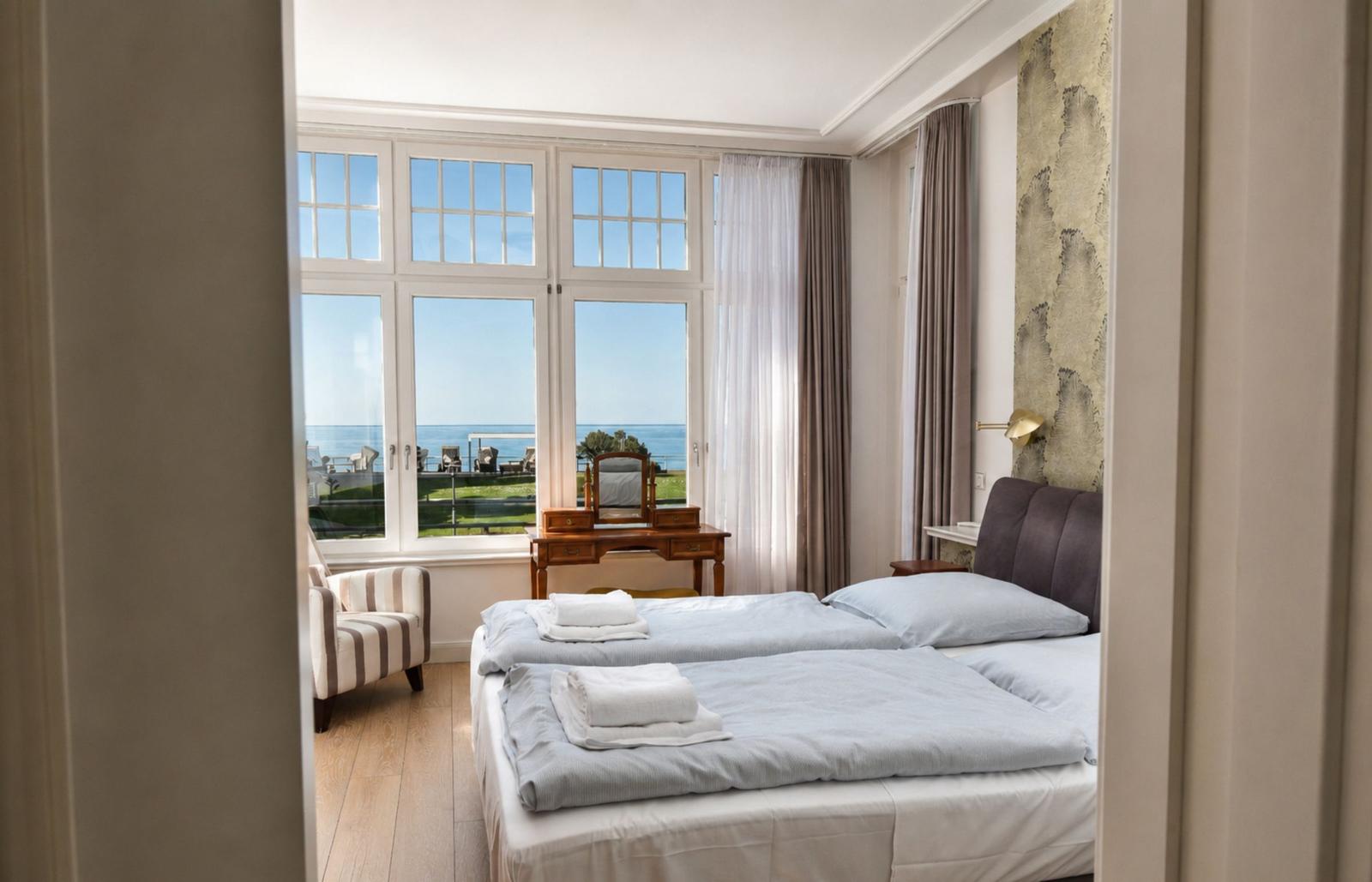 Schlafzimmer mit Blick aufs Meer, Bett, Schreibtisch und Sessel.