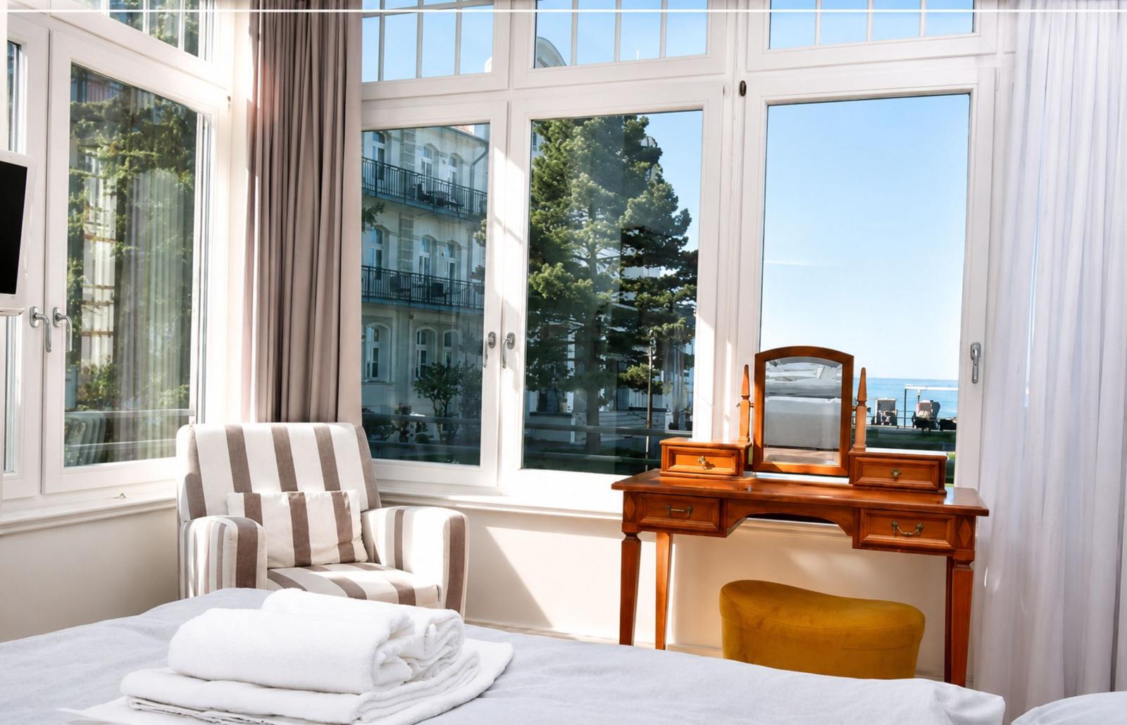 Ein Zimmer mit Blick aufs Meer, einem Schreibtisch und einem Sessel.
