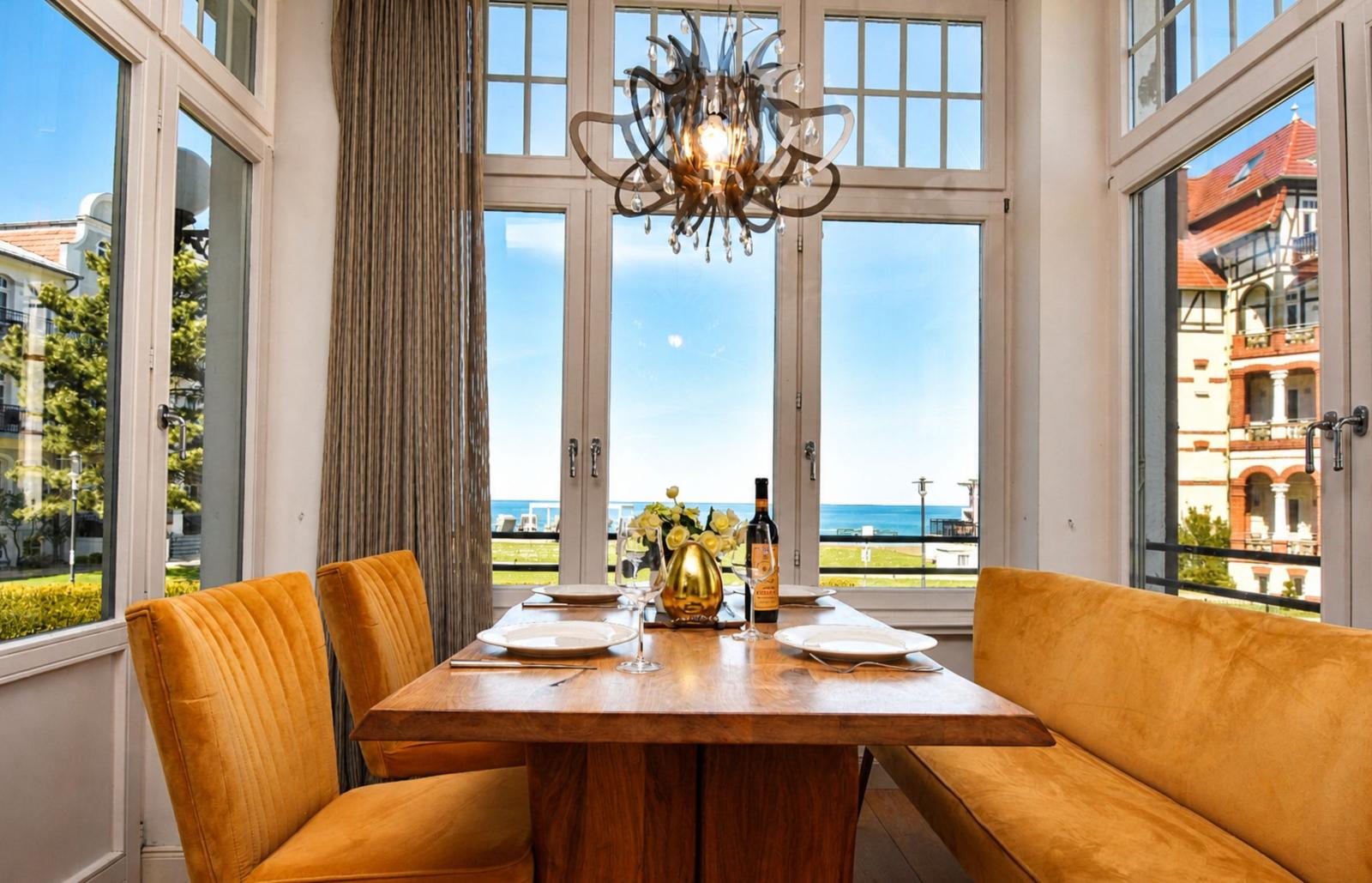 Esstisch mit orangefarbenen Stühlen und Blick aufs Meer.