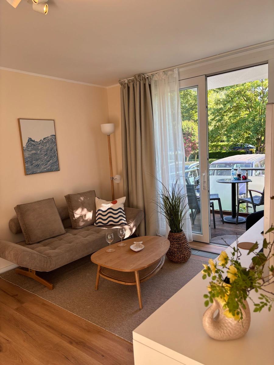 Wohnzimmer mit Sofa, Tisch und Balkon mit Gartenblick.