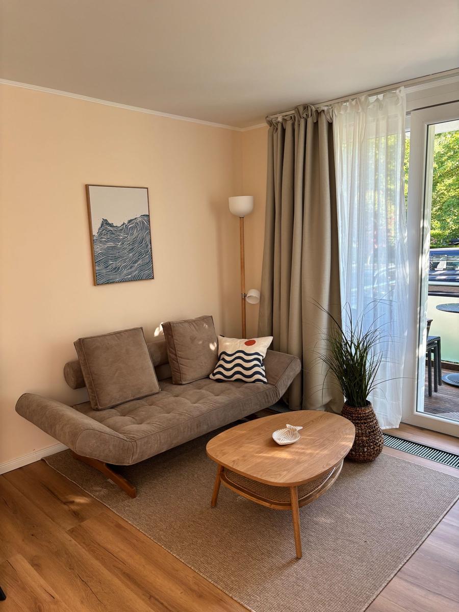 Wohnzimmer mit Sofa, Tisch und Fenster zur Terrasse.
