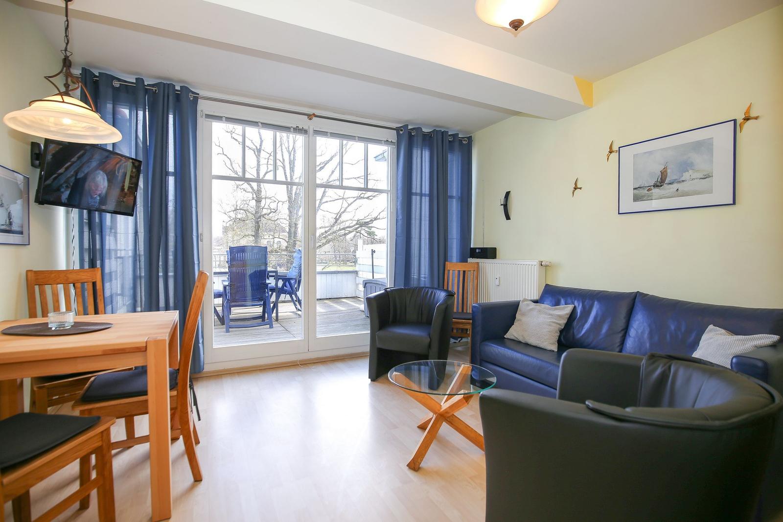 Wohn- und Essbereich mit Sofa, Stühlen und Blick auf Balkon.