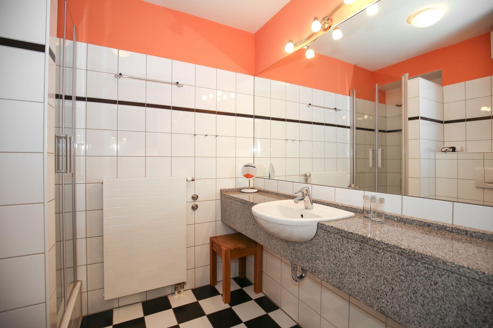 Badezimmer mit Dusche, Waschbecken und Spiegel
