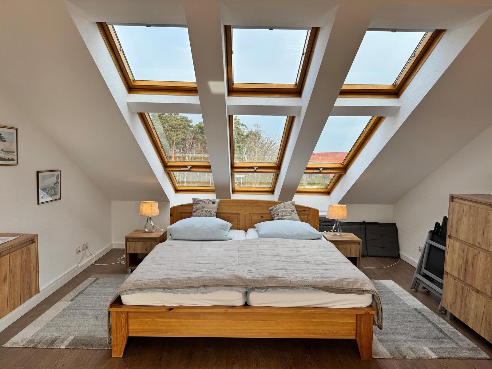 Schlafzimmer mit Dachfenstern, Holzbett und Nachttischen.