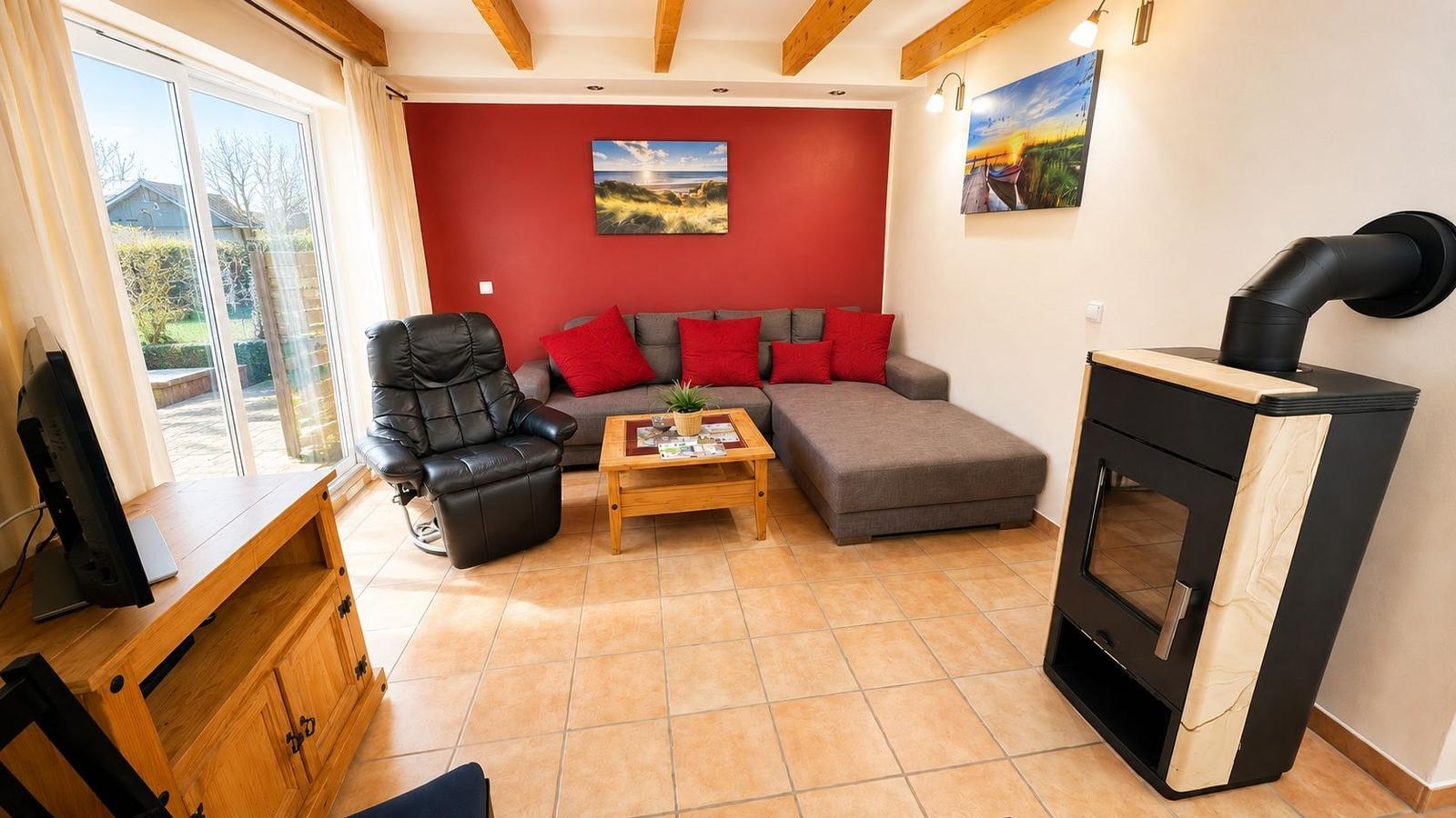 Wohnzimmer mit Sofa, Sessel, Kamin und Blick auf Garten