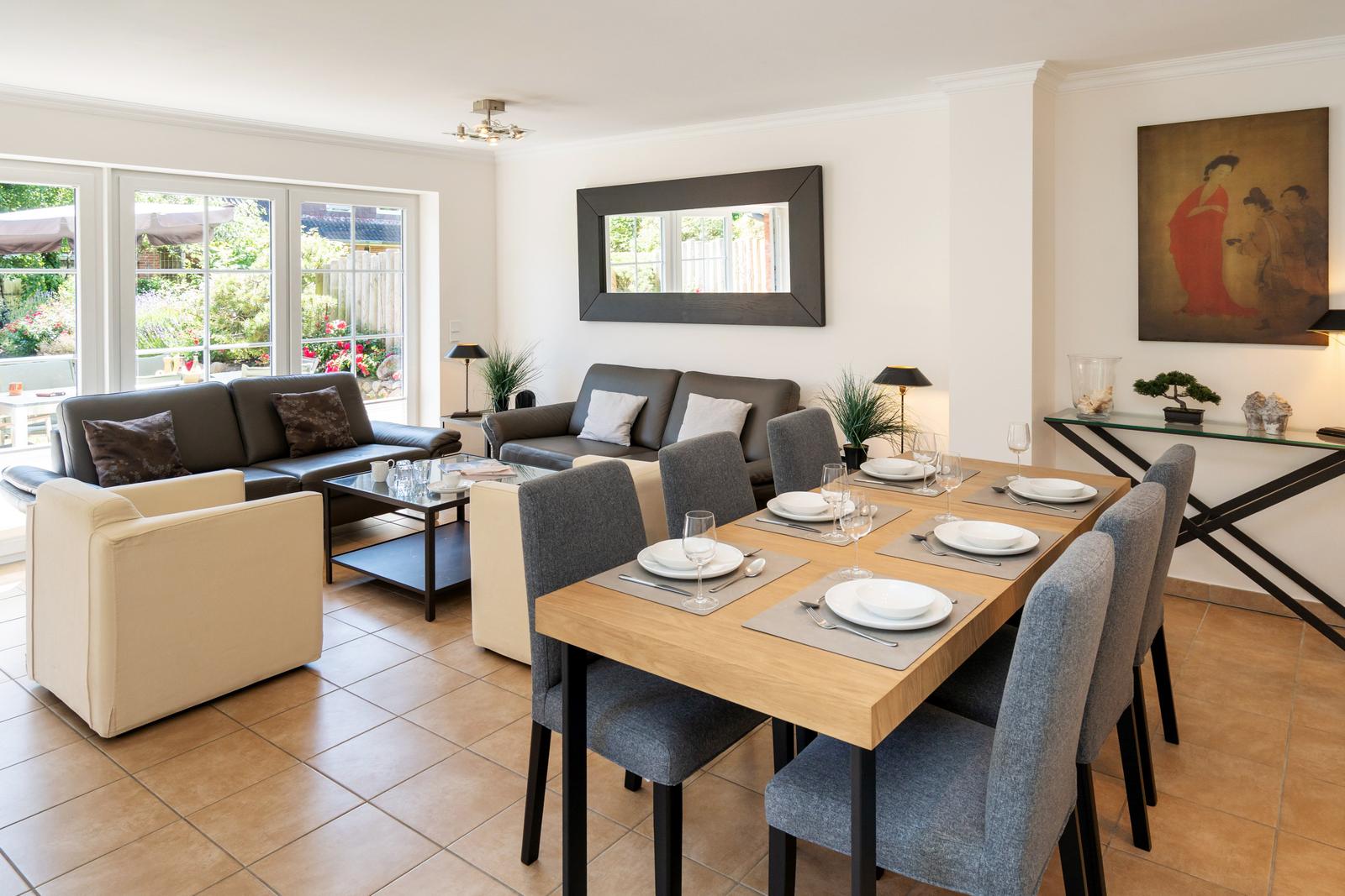Esszimmer mit Tisch und Stühlen. Wohnbereich mit Sofa und Sessel. Fenster zur Terrasse.