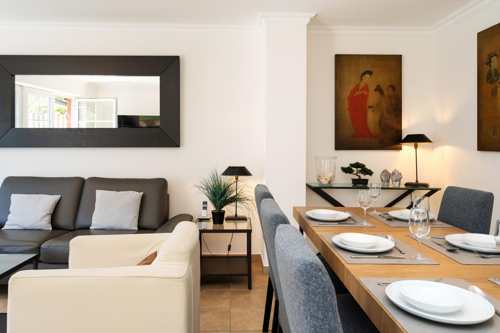 Wohn- und Essbereich mit Sofa, Tisch und Stühlen sowie Wandbildern.