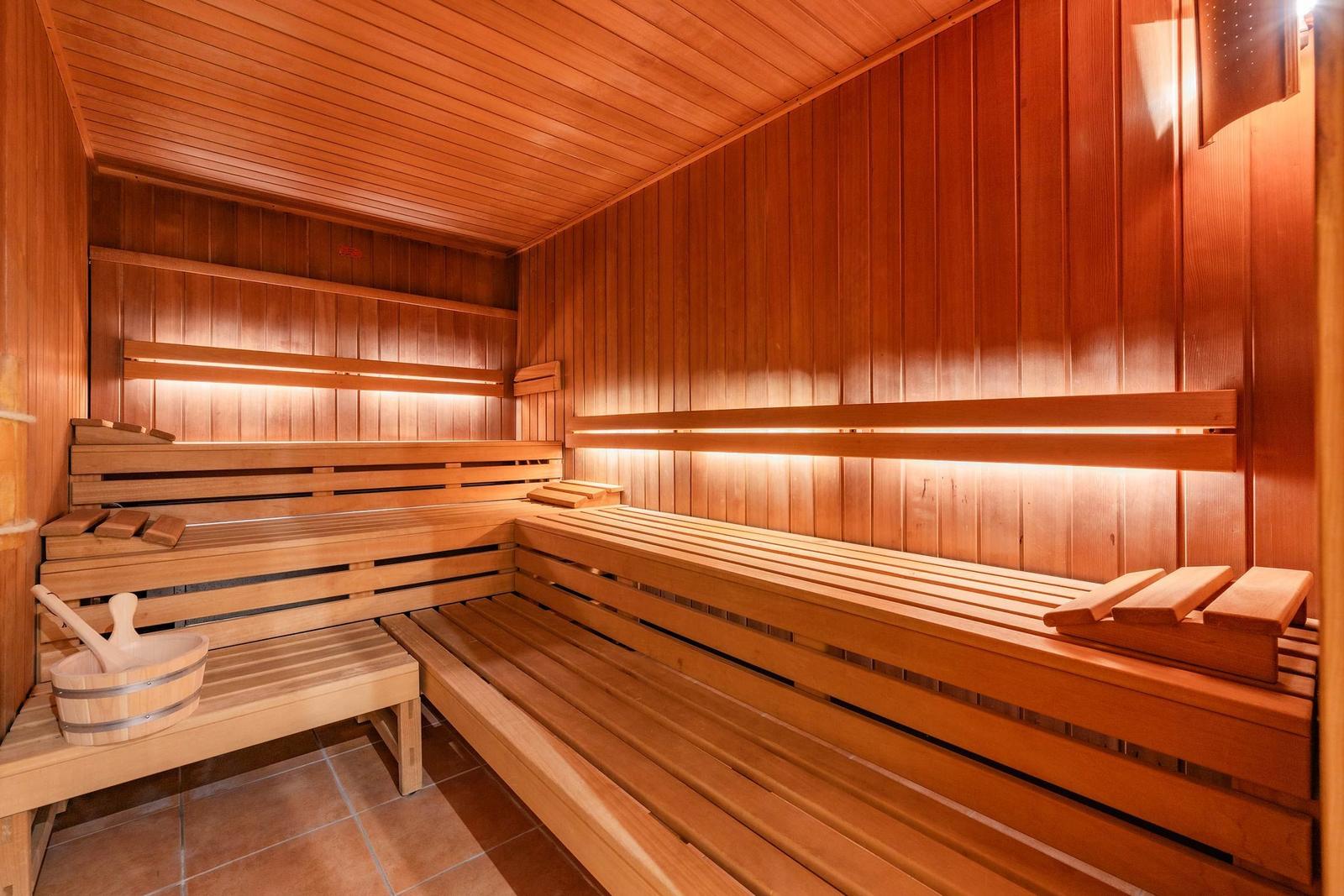 Sauna mit Holzbanken und warmem Licht an den Wänden.