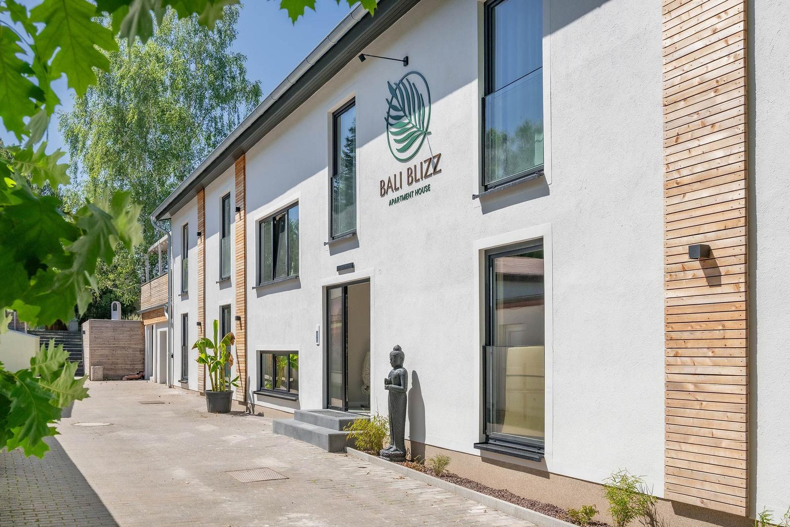 Bali Blizz Apartment House mit moderner Fassade und Buddha-Statue im Eingangsbereich.