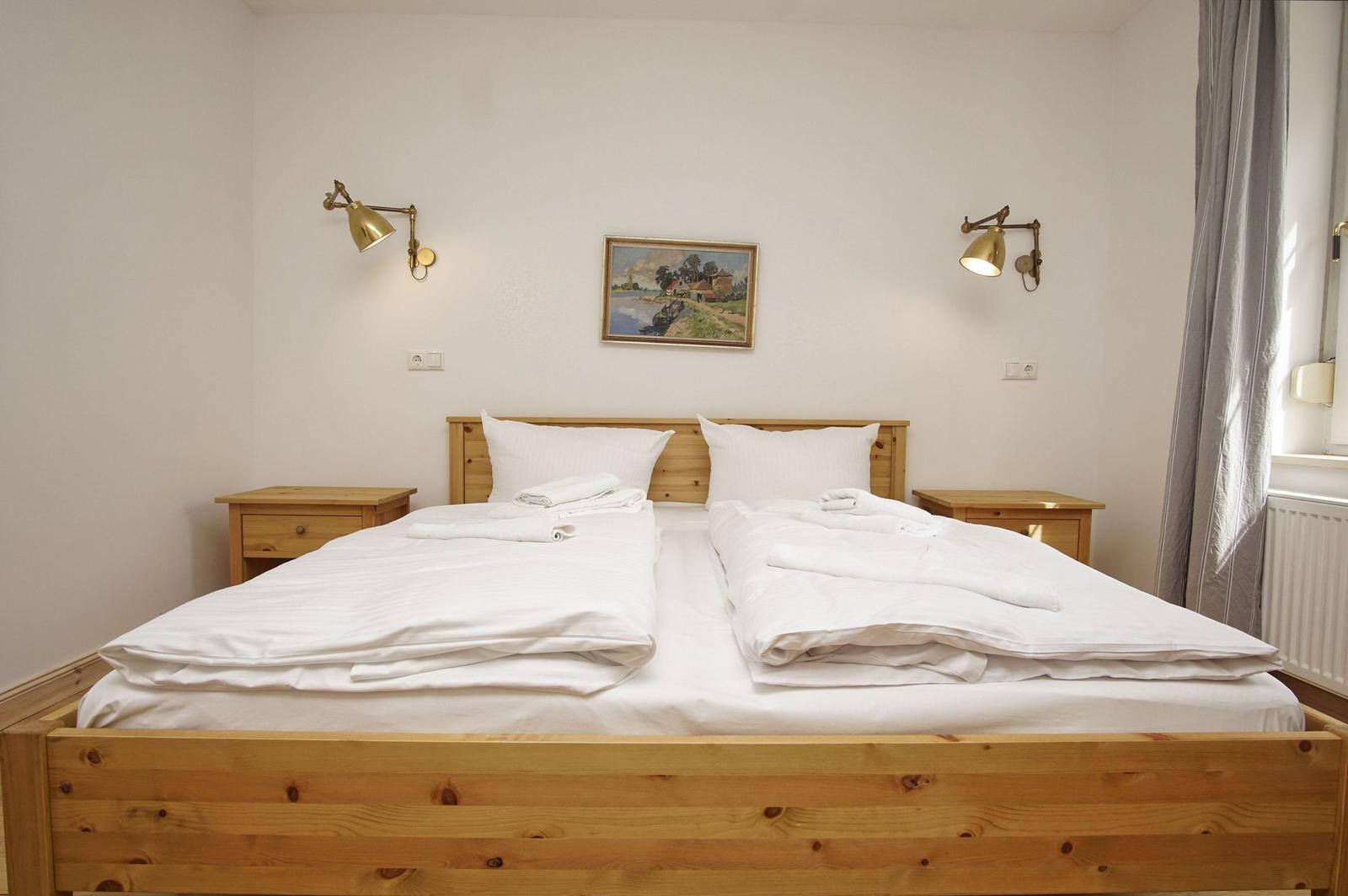 Ein Bett mit weißer Bettwäsche und zwei Nachttischen mit Wandlampen.