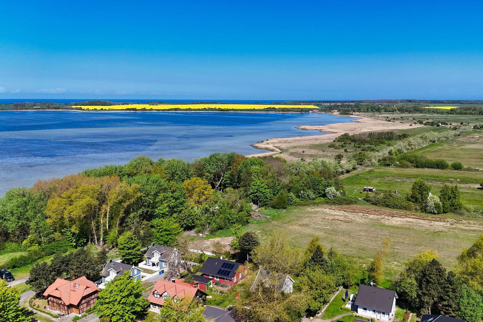Haus mit Blick auf See und Felder unter blauem Himmel.