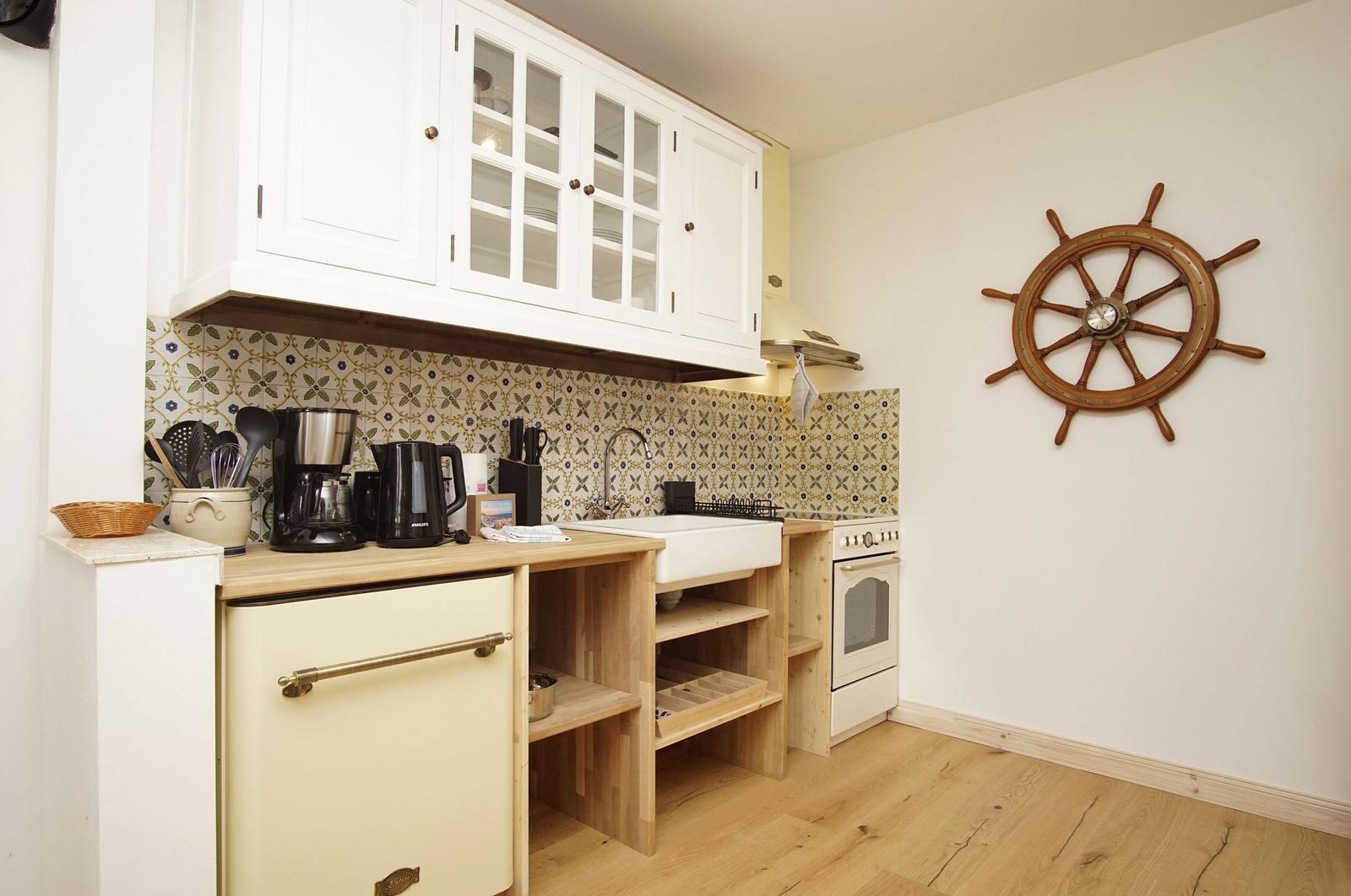 Küche mit weißen Schränken, Holzoberflächen und Segelschiffsruder an der Wand.