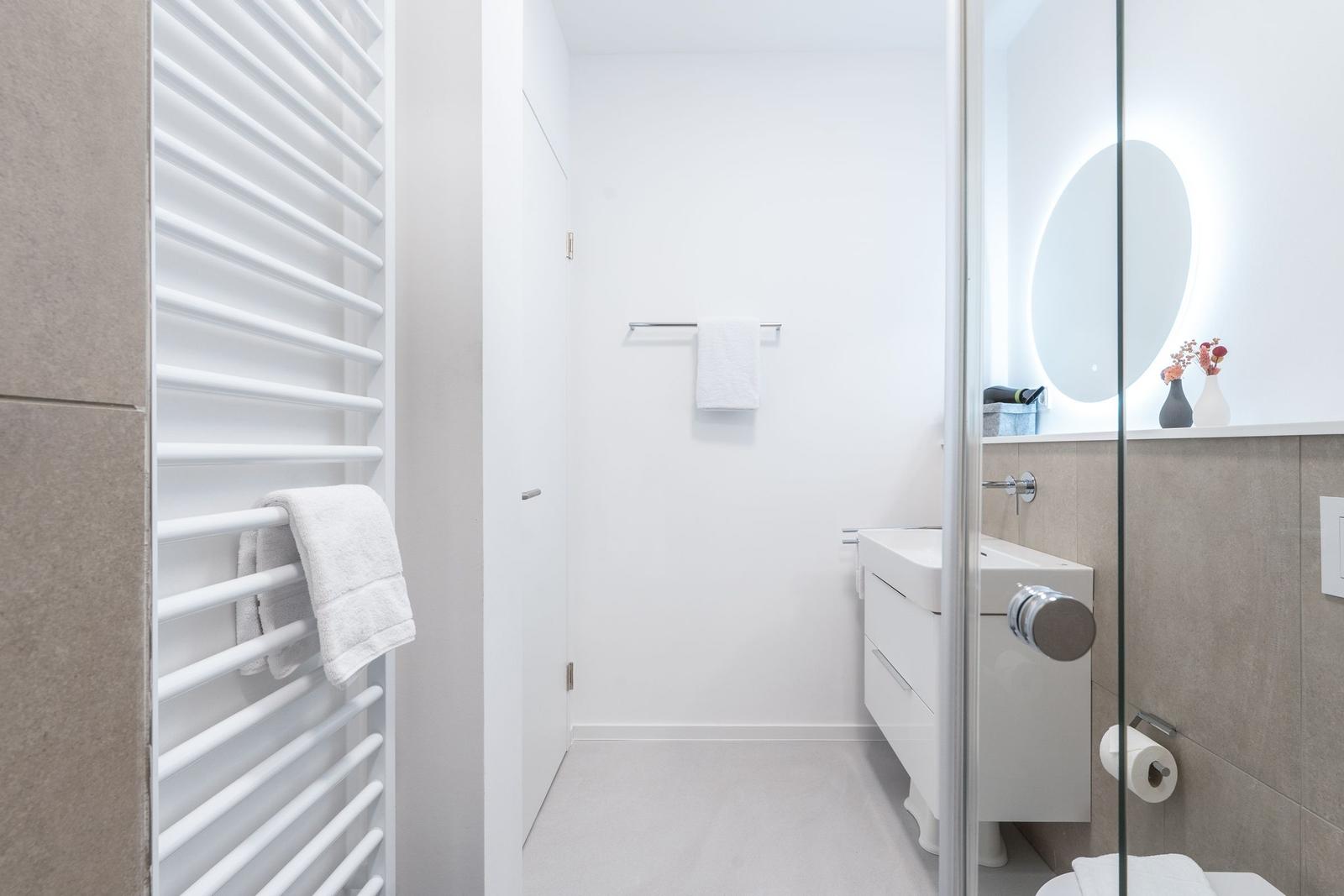 Badezimmer mit Dusche, Waschbecken und Heizkörper