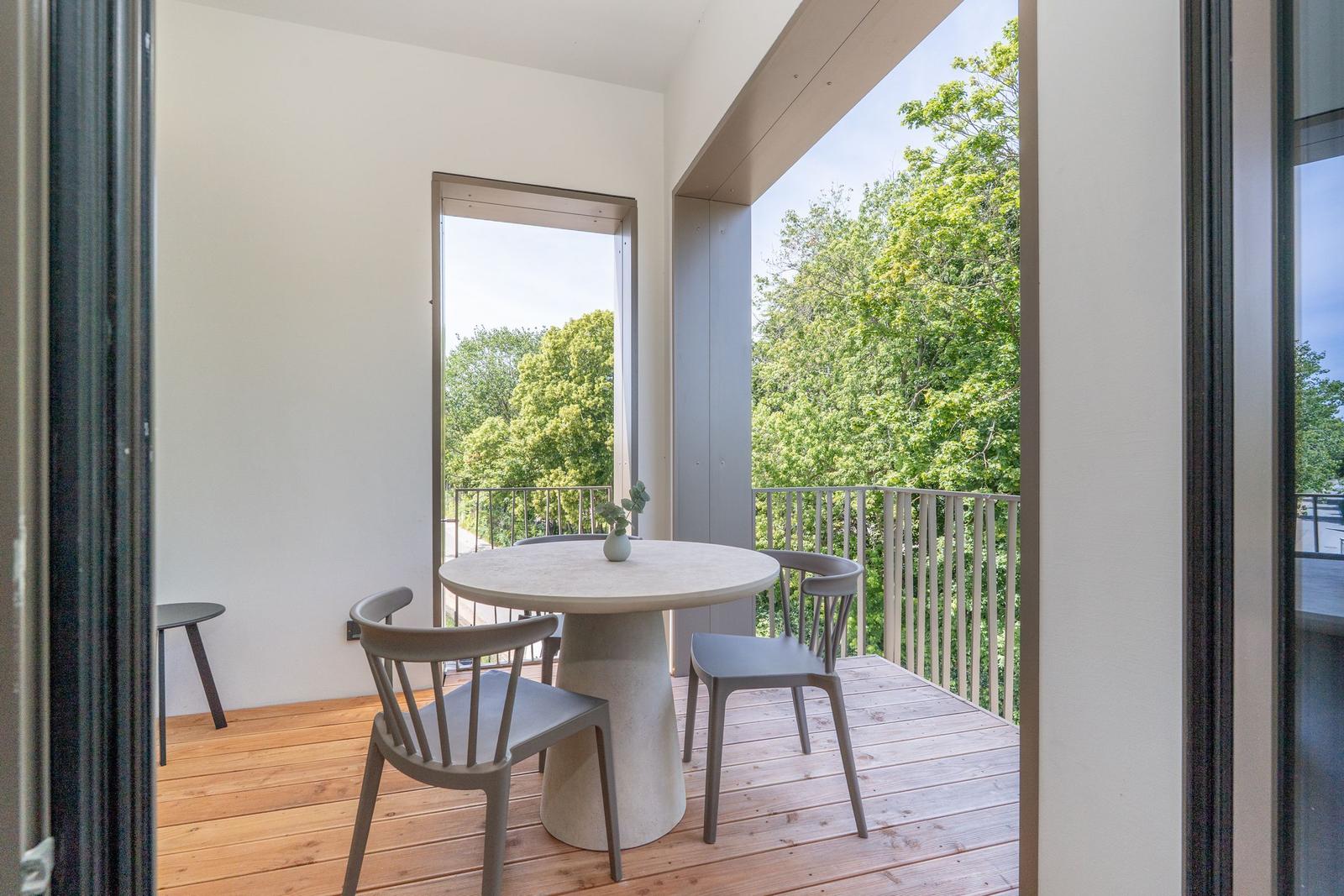 Terrasse mit runden Tisch und Stühlen, Blick auf grüne Bäume