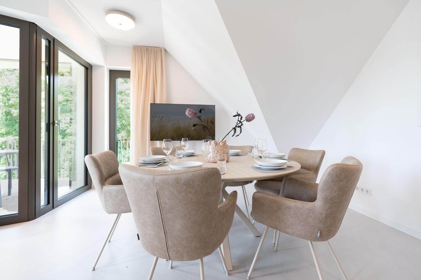 Rundes Esszimmer mit sechs Stühlen und Blick auf Balkon.