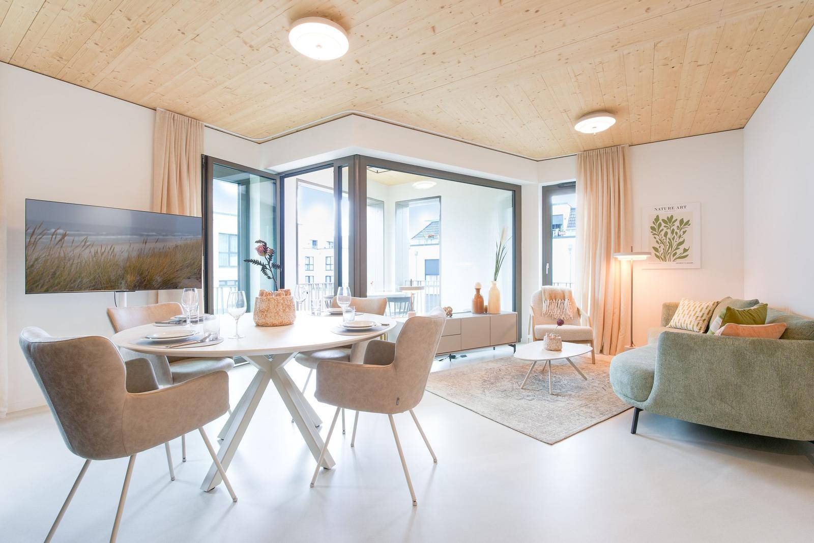 Wohn- und Essbereich mit Holzdecke, Glasfront und modernem Mobiliar.