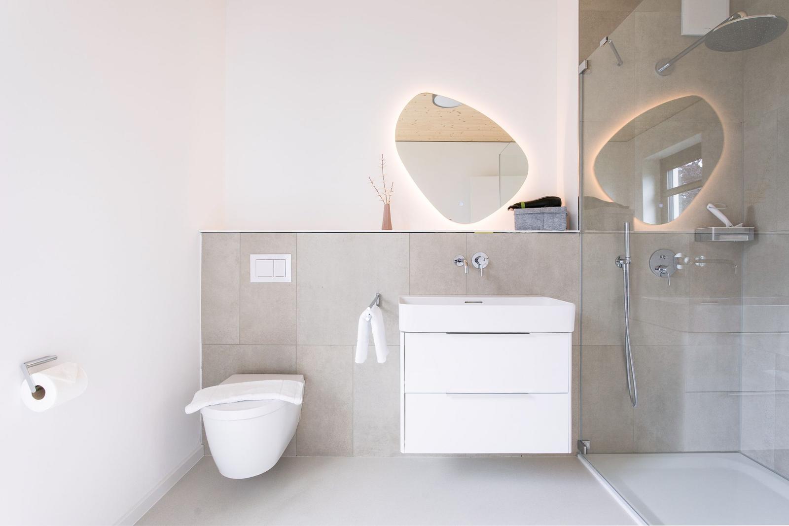 Badezimmer mit Dusche, Waschbecken und Toilette. Modernes Design mit beleuchtetem Spiegel.