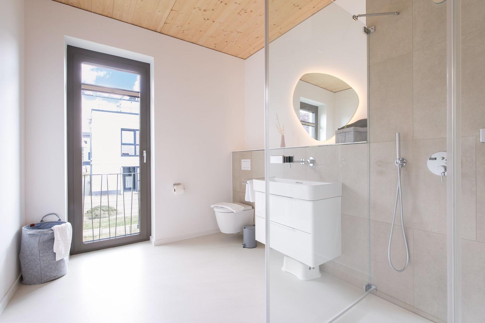 Badezimmer mit Dusche, Waschbecken und Toilette. Fenster mit Blick nach draußen.