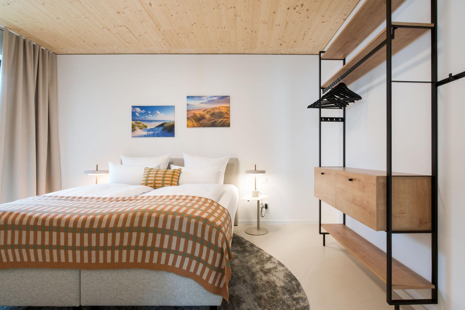 Schlafzimmer mit Bett, Kleiderschrank und Wandbildern