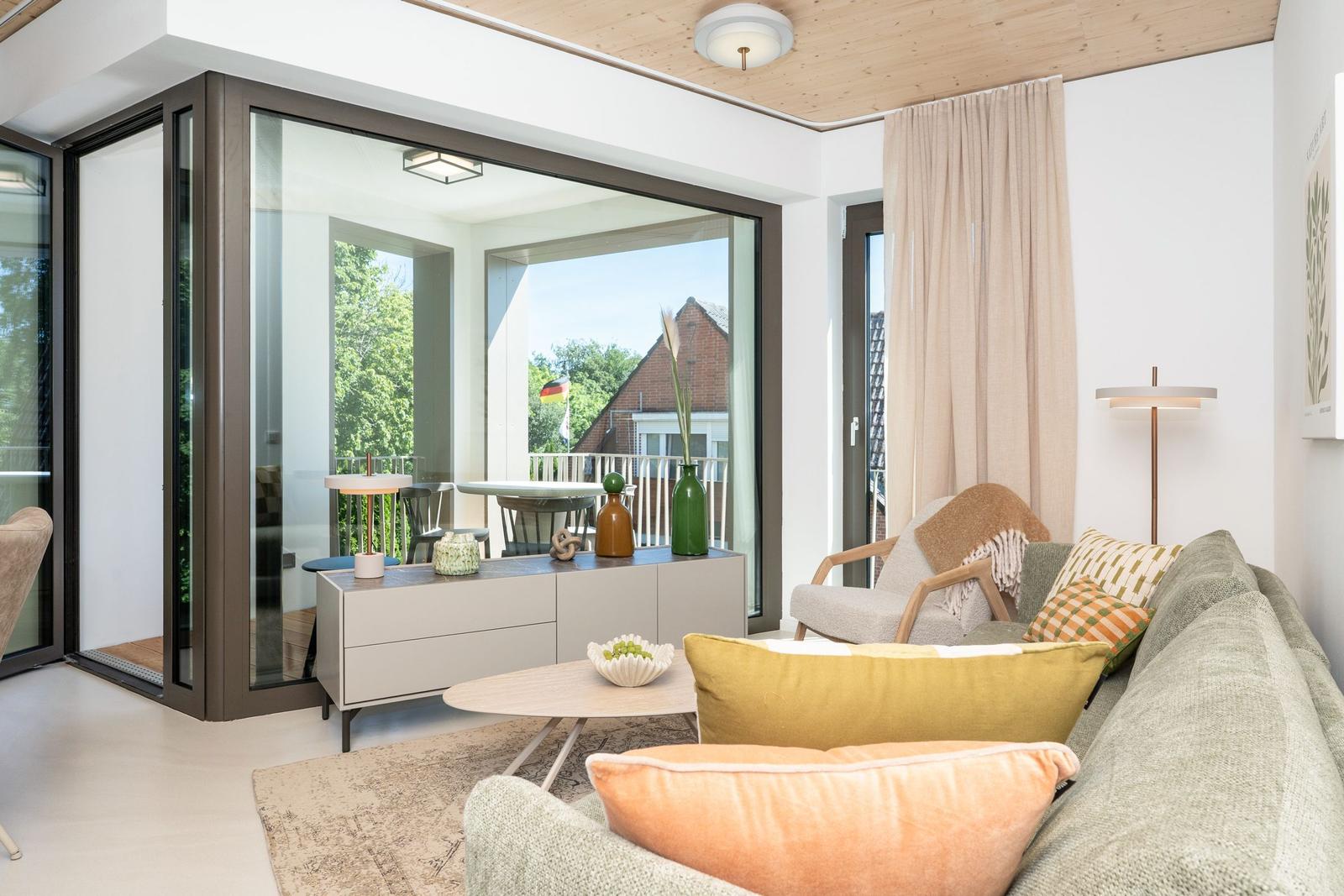 Wohnbereich mit Sofa, Couchtisch und Blick auf Balkon mit Tisch und Stühlen.