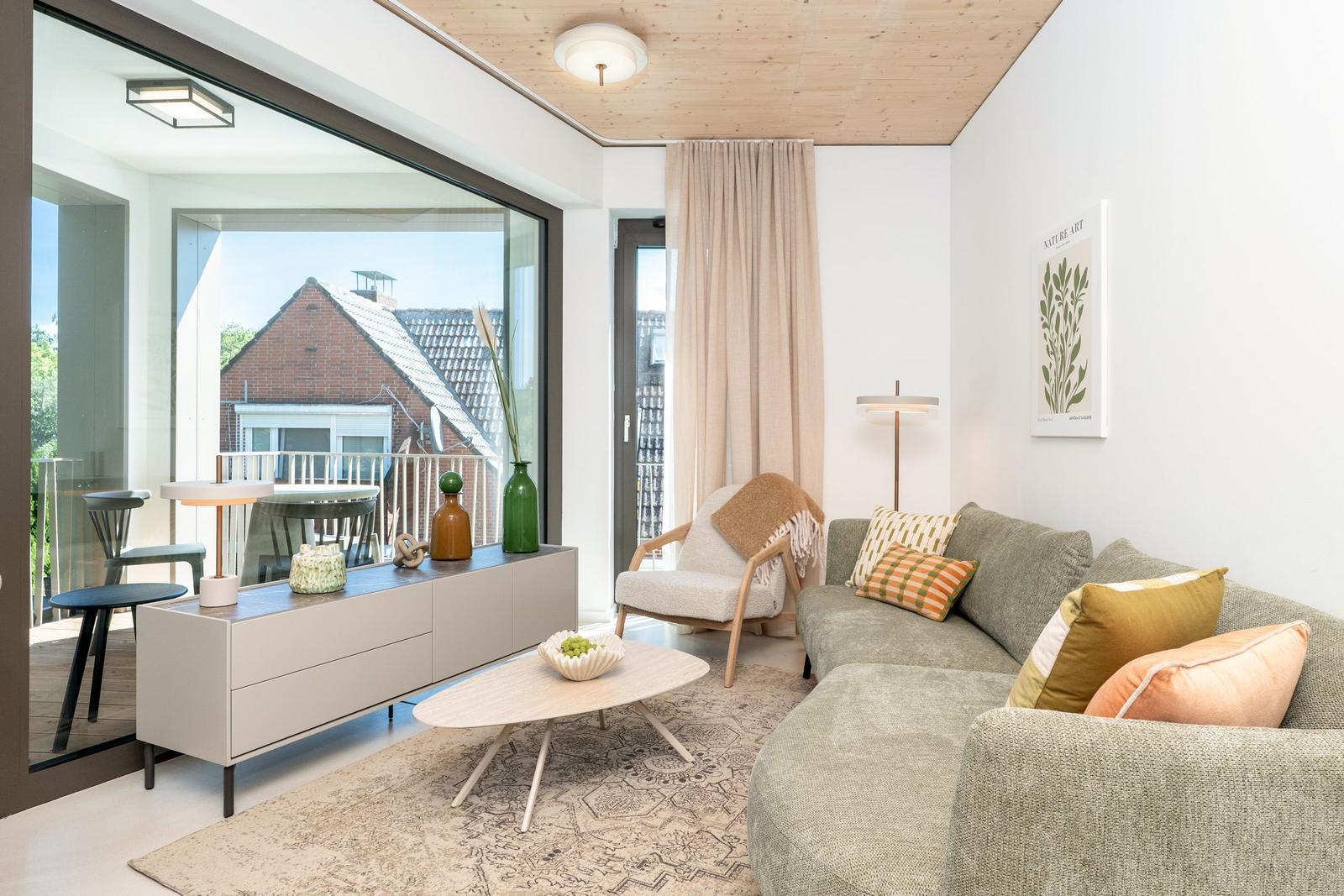 Wohnzimmer mit Sofa, Couchtisch und Blick auf Balkon