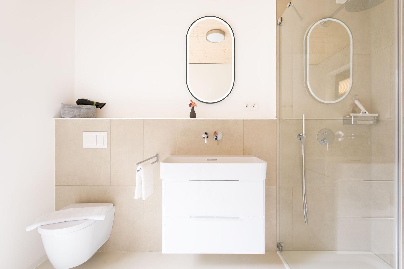 Badezimmer mit Dusche, Waschbecken und Toilette. Moderne Einrichtung und hellen Farben.