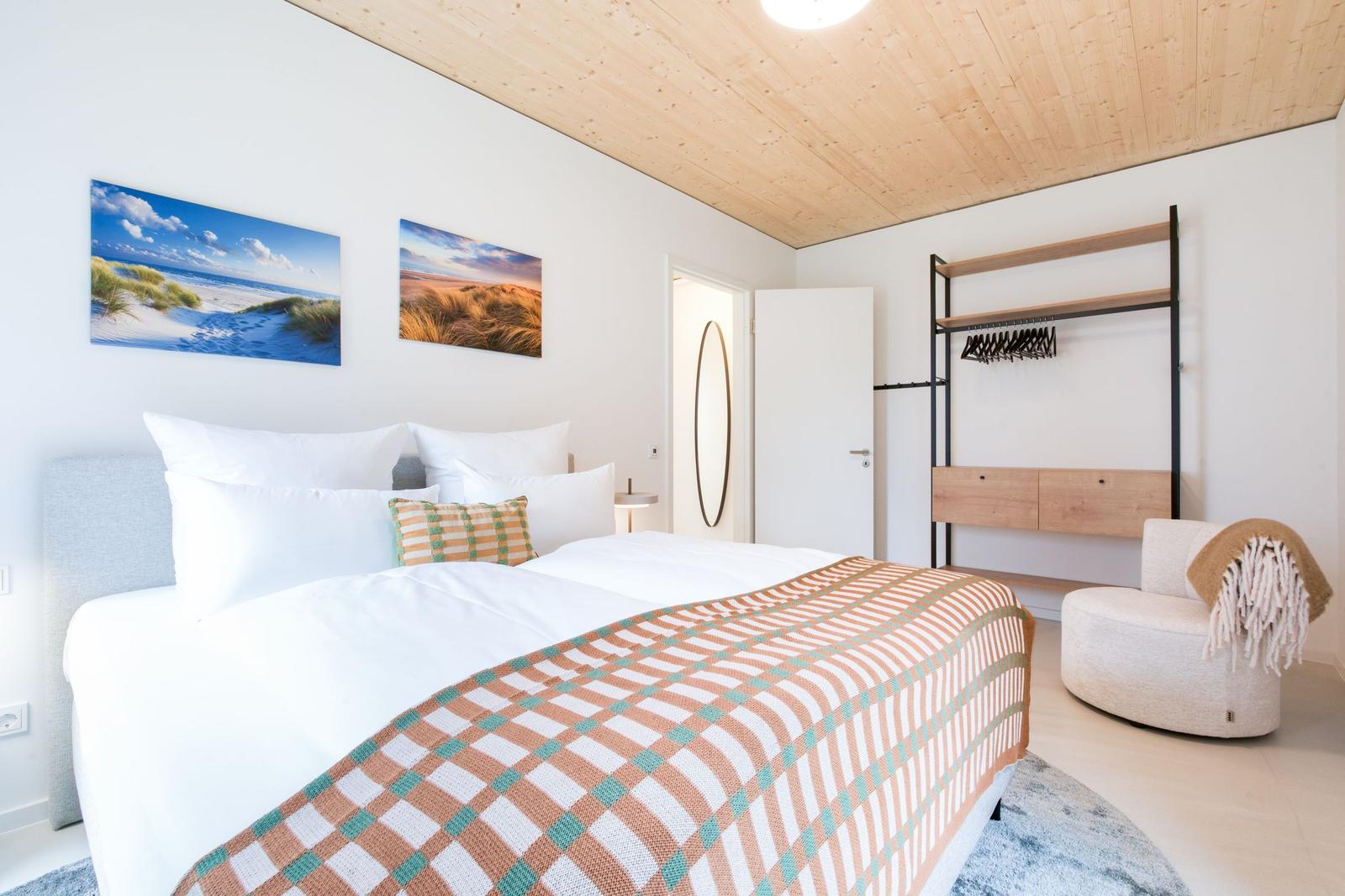 Schlafzimmer mit Bett, Kleiderschrank und Wandbildern