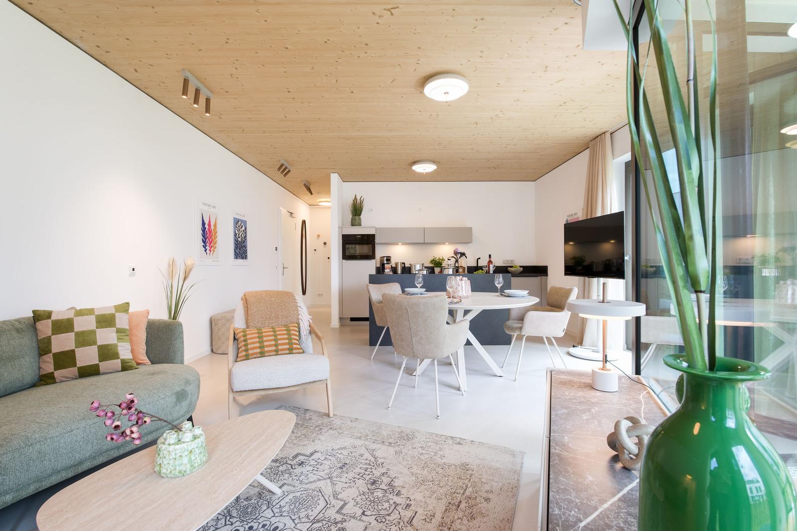 Wohn- und Essbereich mit Holzdecke, Sofa, Stuhl, Tisch und Fernseher.
