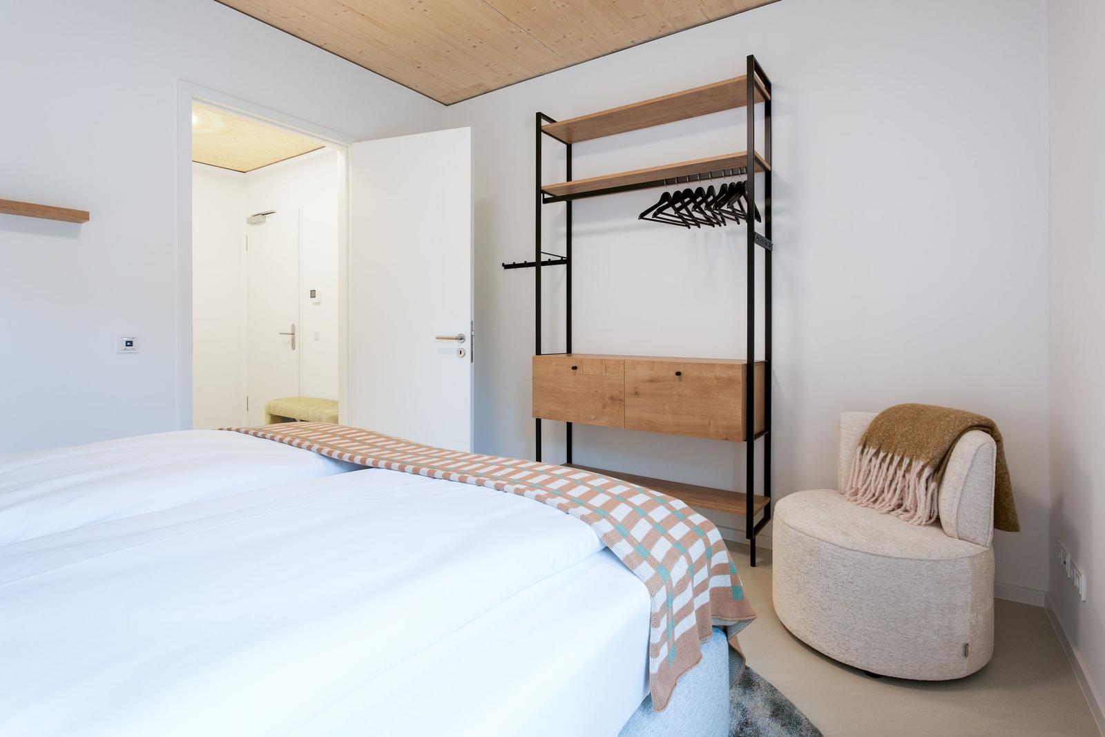Schlafzimmer mit Bett, Kleiderschrank und Sessel.