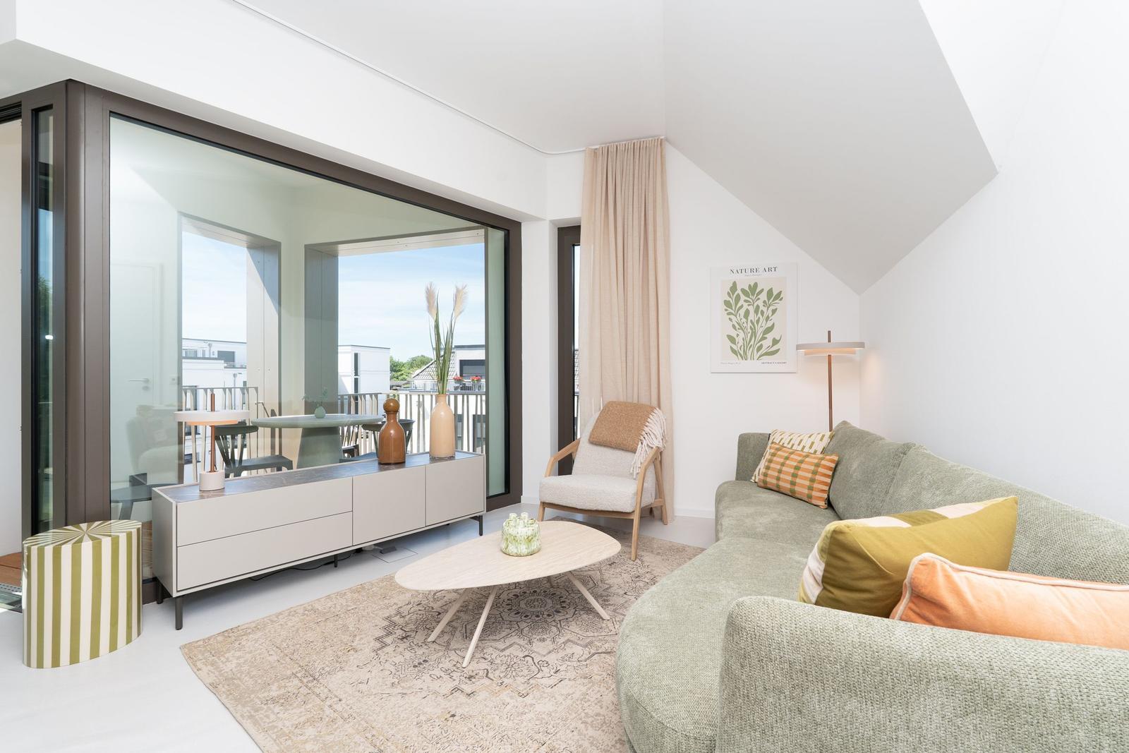 Wohnzimmer mit Sofa, Couchtisch und Blick auf Balkon.