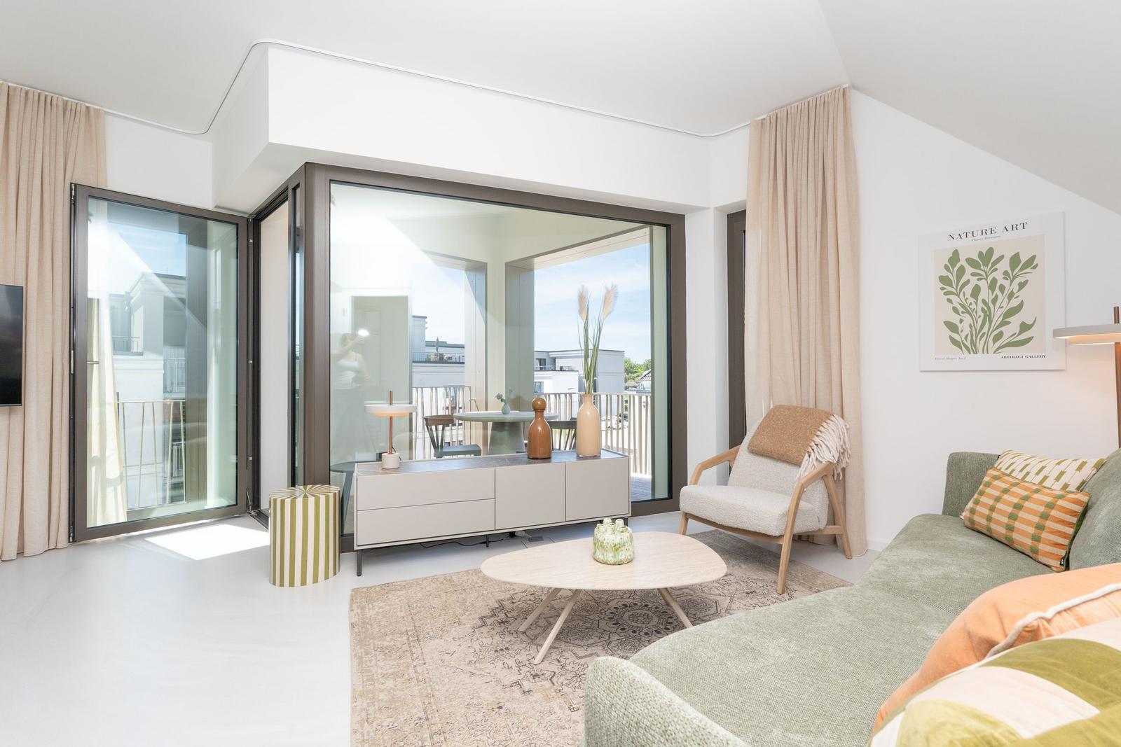 Wohnzimmer mit Sofa, Sessel und Glasfront zur Terrasse.