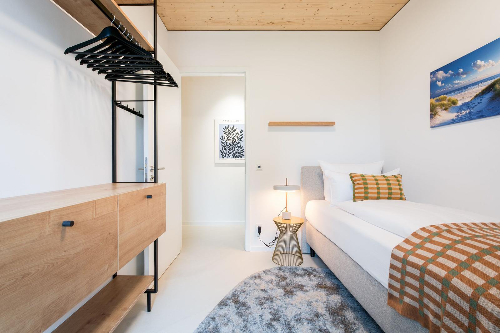 Schlafzimmer mit Bett, Kleiderschrank und Wandbild