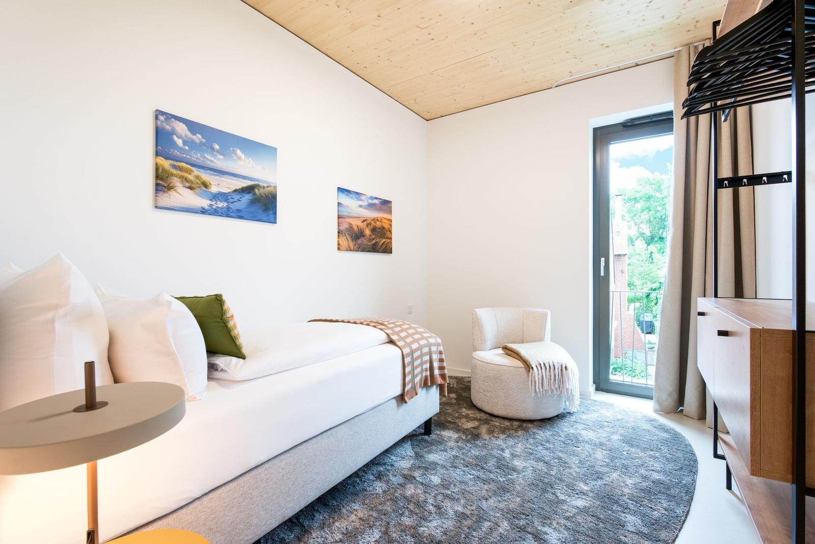 Schlafzimmer mit Bett, Sessel und Fenster zur Aussicht