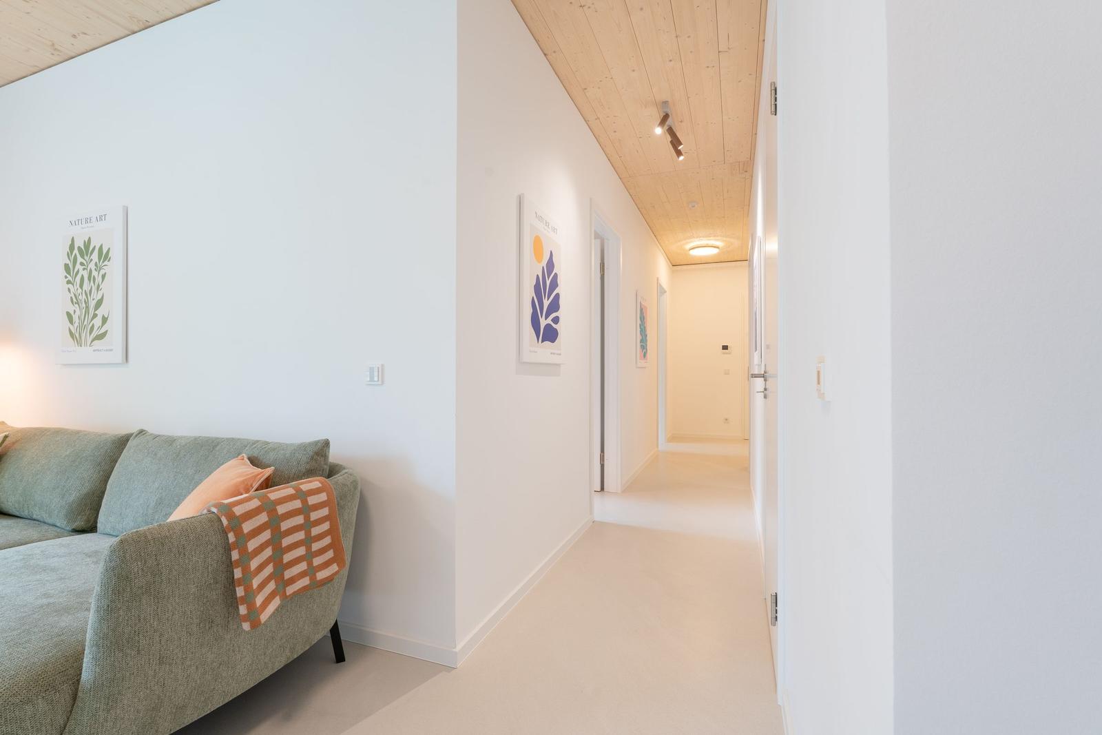 Wohnbereich mit Sofa und Flur mit Holzdecke und Wandbildern.
